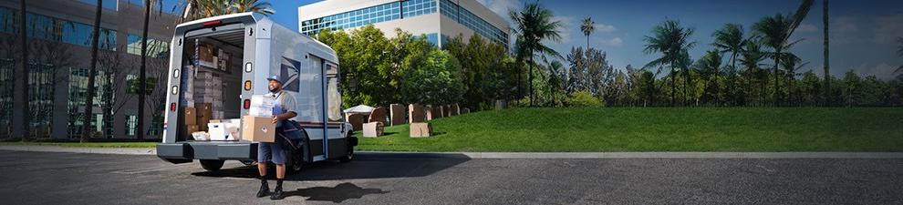 Letter carrier ready to deliver packages unloaded from the back of a 美国邮政总局 Next-Generation Delivery Vehicle.